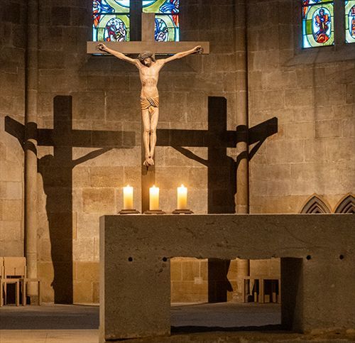 Photographie des Kreuzes mit den beiden unterschiedlich dunklen Schatten, davor der Altar von Ulrich Rückriem